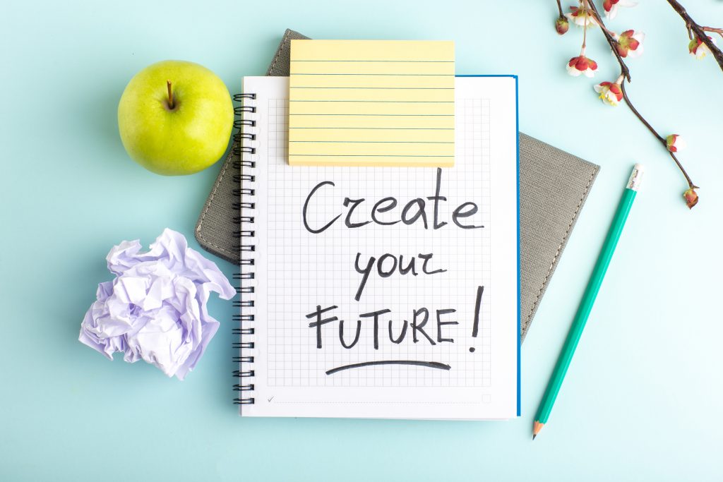 Flatlay - Apfel, Stift und Block mit der Aufschrift Create your Future